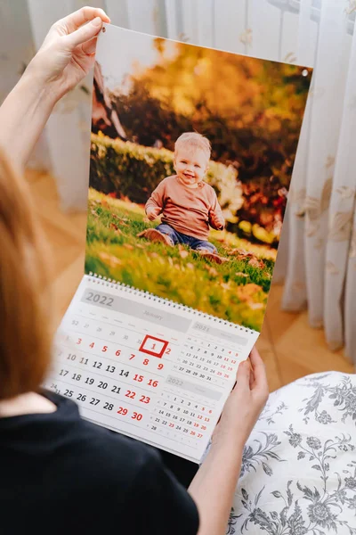 Mujer sosteniendo en sus manos calendario para 2022 con una foto del niño. — Foto de Stock