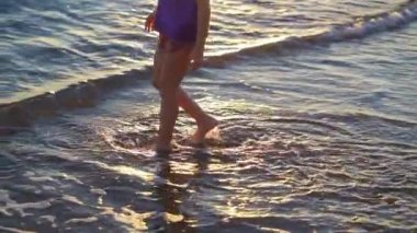 Küçük kız deniz kıyısında yürüyor, taş topluyor ve suya atıyor..