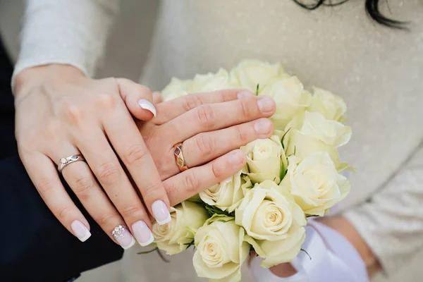 Manos de hombre y mujer con anillos de boda en el fondo del ramo de la boda. — Foto de Stock