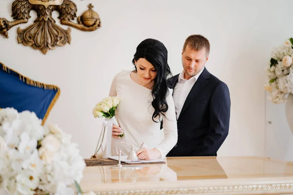 Braut und Bräutigam im Standesamt unterzeichnen offizielle Trauanmeldung. — Stockfoto