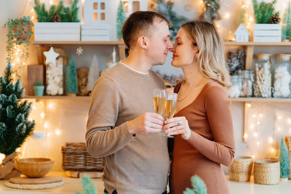 Um casal apaixonado por copos de champanhe na cozinha de Natal. romântico. — Fotografia de Stock