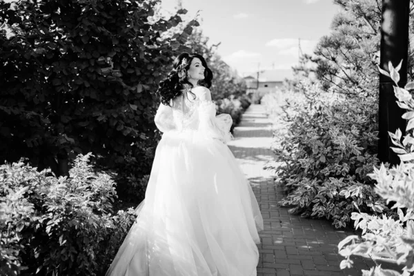 Blick von hinten. eine Braut, die im Hochzeitskleid einen Weg im Park hinunterläuft. — Stockfoto