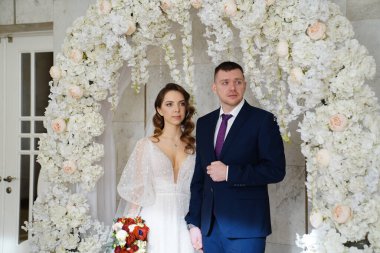 Gelin ve damat düğün töreninde çiçek kemerinde. İnsanlar mutluluktan ağlar.