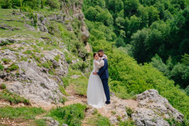 Dağ ormanlarının arka planına karşı güzel yeni evliler. Dağlarda düğün. 