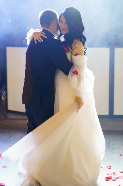 A noiva e o noivo em vestidos de casamento dançam em um corredor escuro na fumaça pesada. — Fotografia de Stock