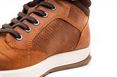 Kahverengi deri botların beyaz arka planda bağcıkları var.