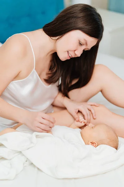 Mamma i sängen bredvid en sovande bebis. Moderskapets lycka.. — Stockfoto