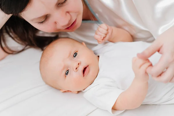 Mamá se acuesta con el bebé en la cama. la felicidad de la maternidad. —  Fotos de Stock