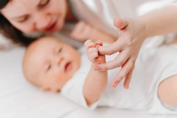 En foco pequeño babys mano y las madres mano en la hoja blanca. mamá y recién nacido. — Foto de Stock