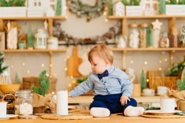 Yeni yıl süsü verilmiş bir çocuk mutfağın tezgahında oturuyor..