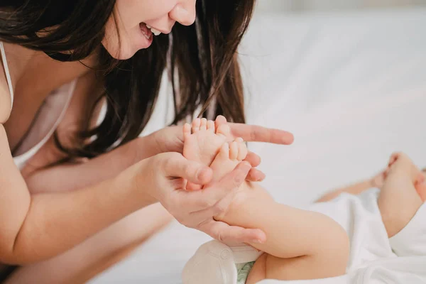 Una madre gentil y cariñosa mantiene las piernas del bebé. — Foto de Stock