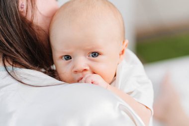 Sevimli bir çocuk annesinin omzunun üstünden bakıyor..