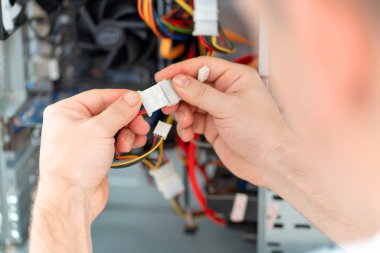 Arkadan bak. Bir adam atölyedeki bilgisayarı tamir ediyor. Arkadan görünüm