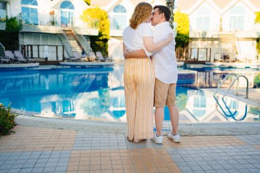 Arkadan bak. Bir adam ve bir kadın havuz kenarında villada. 