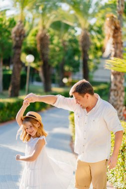 Bir baba ve kızı tropikal bir parkta dans ediyorlar. Babaların ve çocukların tavırları