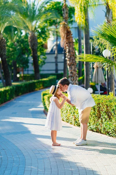  Babam kızlarının yüzünü nazikçe tutuyor Tropikal bir parkta elleri ile