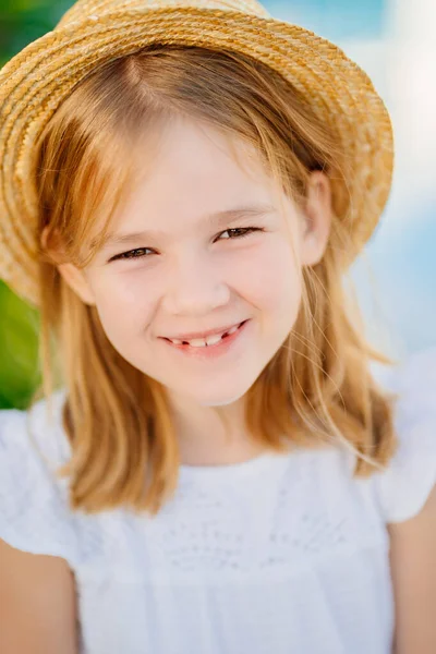 Porträtt av en glad liten flicka med blont hår i en halmhatt. — Stockfoto