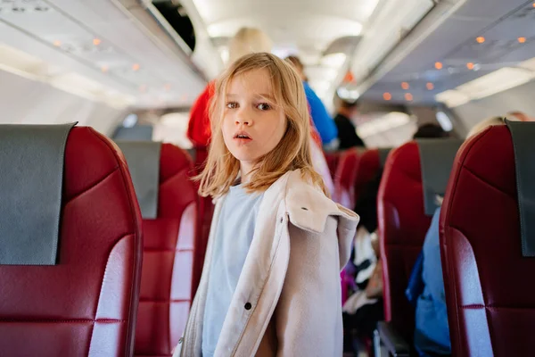 A little girl stands in the aisle of the plane. travel with children — 图库照片