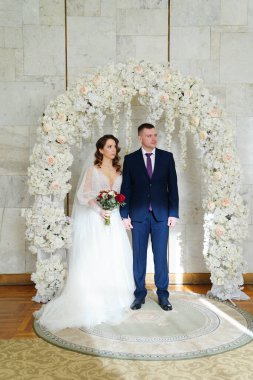 Güzel ve mutlu gelin ve damat düğün töreninde bir çiçek kavisinde