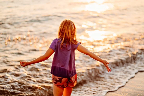 На закате. Девочка ходит по берегу моря, собирает камни и бросает их в воду. — стоковое фото
