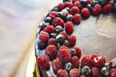 Yuvarlak çikolatalı pastanın bir parçası. Taze ahududu ve yabanmersinli.