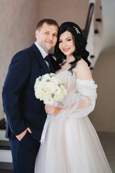 Наречений і наречений у весільному одязі з букетом квітів стоять разом — стокове фото
