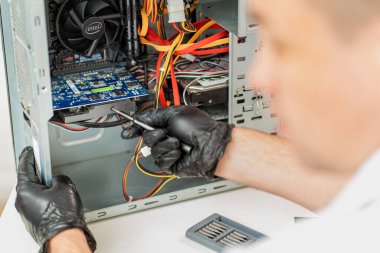 Bir adam atölyedeki bilgisayarı tamir ediyor. Arkadan görünüm