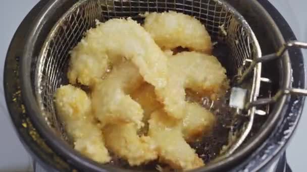 De la friteuse sortir un panier avec des crevettes frites en pâte. — Video