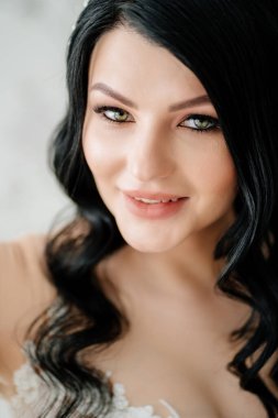 Yakın plan. Beyaz elbiseli güzel esmer gelin. Gelin için saç ve makyaj.