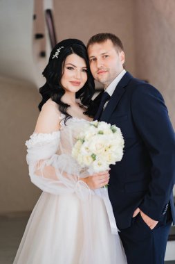 Gelin ve damat bir buket çiçekle birlikte dururlar.