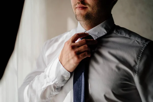 Männerhände binden sich eine Krawatte um den Hals über einem weißen Hemd. — Stockfoto