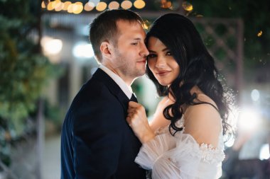 nazik ve mutlu gelin ve damat akşam caddesinde gelinlik içinde.