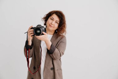 Beyaz arka plandaki esmer kadın fotoğraf çekiyor, mankenle çalışıyor.