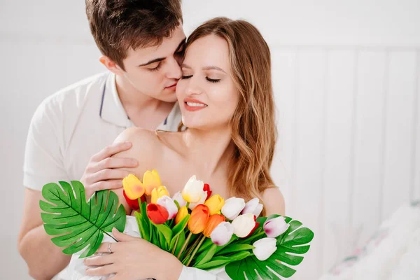 Ein Mann schenkte seiner geliebten Frau einen Strauß bunter Tulpen. Sanfter Kuss — Stockfoto