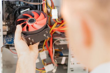 Bilgisayar atölyesi. Tamircinin eli bilgisayara soğutucu yerleştirir