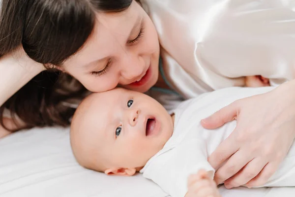 Mom lies with the baby in bed. the happiness of motherhood. — Stock Photo, Image