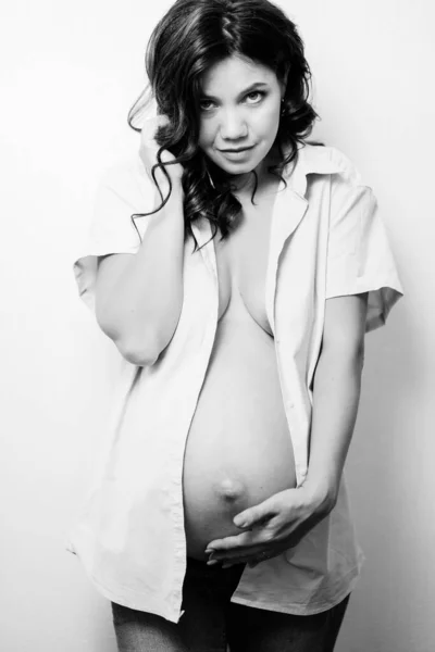 Attractive pregnant woman in jeans and a shirt on a naked body. womens health — Stockfoto