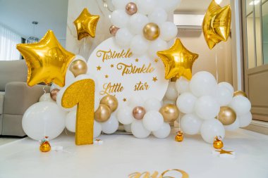 Beyaz ve altın balonların ilk doğum günü için bir fotoğraf bölgesi ve bir figür. 