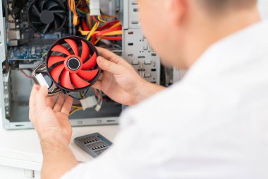 Bilgisayar atölyesi. Tamircinin eli bilgisayara soğutucu yerleştirir