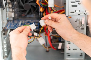 Arkadan bak. Bir adam atölyedeki bilgisayarı tamir ediyor. Arkadan görünüm