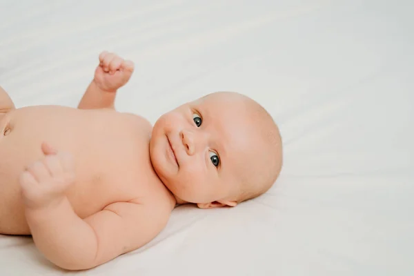 Bebê bonito sem roupas em um lençol branco. pediatria. pele saudável — Fotografia de Stock