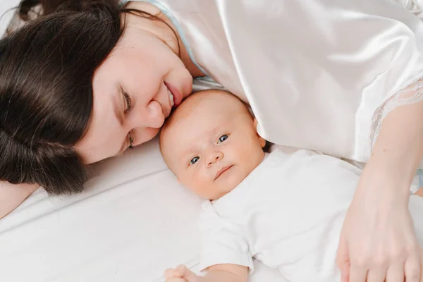 Mamá se acuesta con el bebé en la cama. la felicidad de la maternidad. —  Fotos de Stock