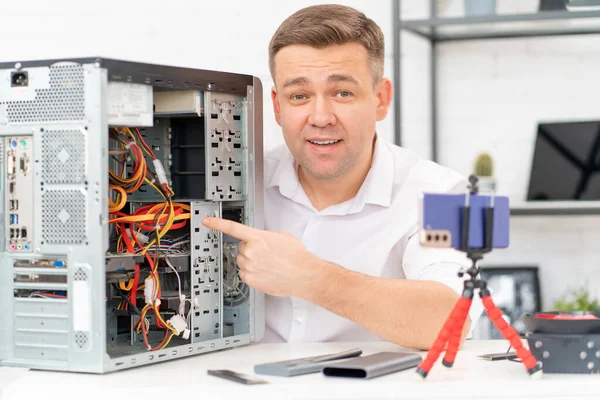 Um homem registra uma lição de vídeo sobre reparação de computadores ou faz uma consulta on-line. — Fotografia de Stock