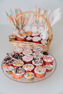 basket with decorated eggs and Easter cakes or muffins on the table.