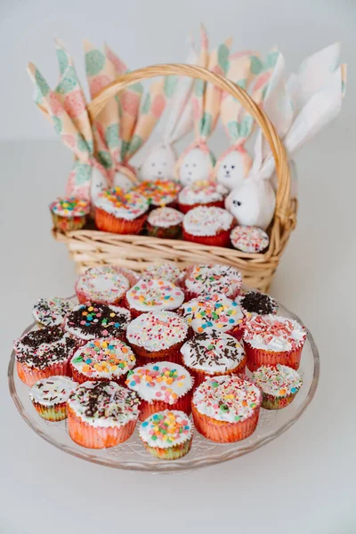 Basket with decorated eggs and Easter cakes or muffins on the table. — Stock fotografie