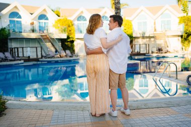 Arkadan bak. Bir adam ve bir kadın havuz kenarında villada. 