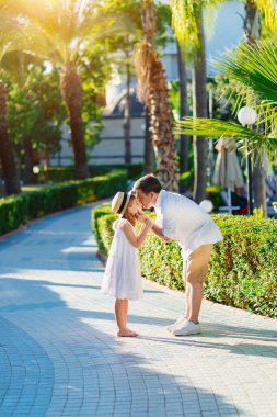  Babam kızlarının yüzünü nazikçe tutuyor Tropikal bir parkta elleri ile