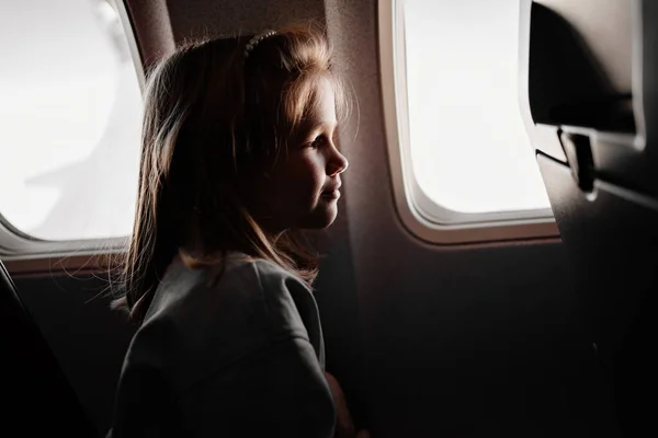 Uma menina senta-se em um assento de avião pela janela. — Fotografia de Stock