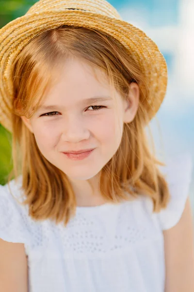 Portrait of a cute little girl with blonde hair in a straw hat. — Stockfoto
