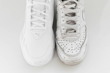 Puma ve Nike. Beyaz arka planda bağcıkları olan eski ve yeni beyaz spor ayakkabılar..